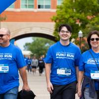 Individuals near finish line smiling as they cross under arch
